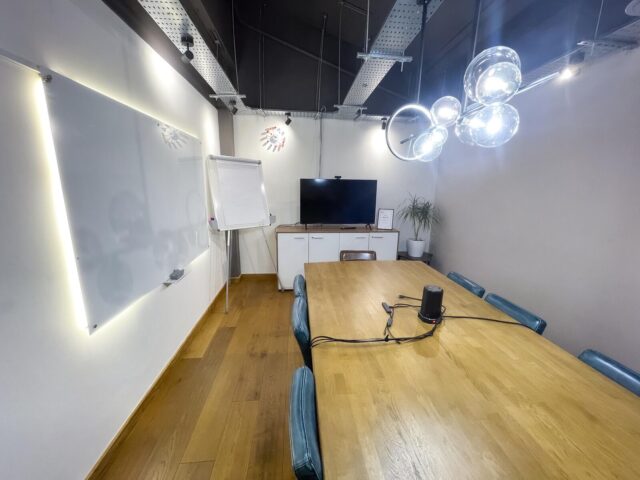 The Orbit meeting room featuring a spacious boardroom table, leather seating for up to 14 and a large screen for presentations in a modern Shoreditch workspace.