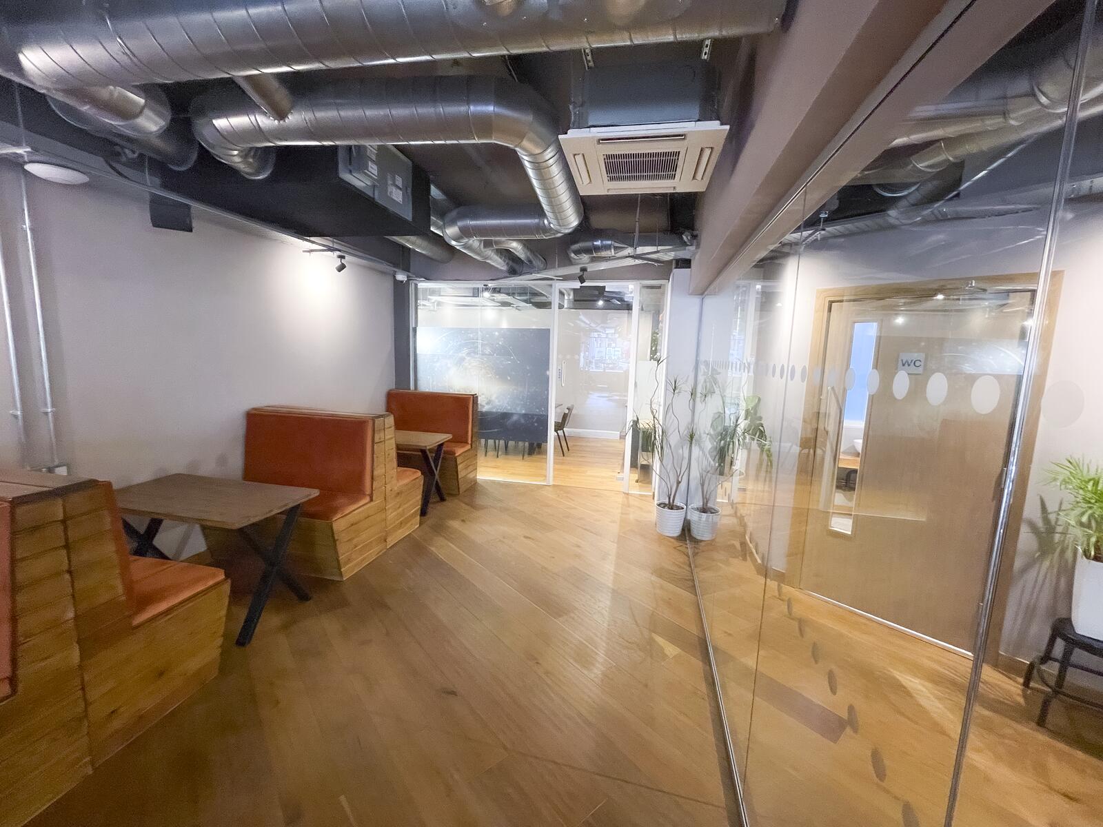 Open-plan perspective of The Lower Deck with glass partitions, wooden flooring and industrial ceiling design.